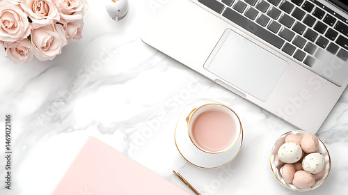 A laptop is on a table with a cup of tea and a bowl of cookies