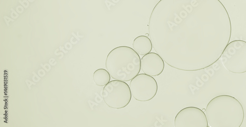 close-up view oil and water droplets forming patterns in pale green  liquid under magnification textured background.