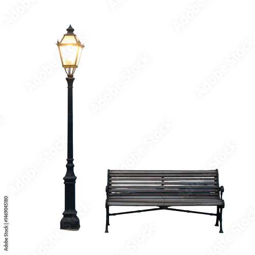 A street lamp illuminating a dark scene next to a bench with a black background in the night time