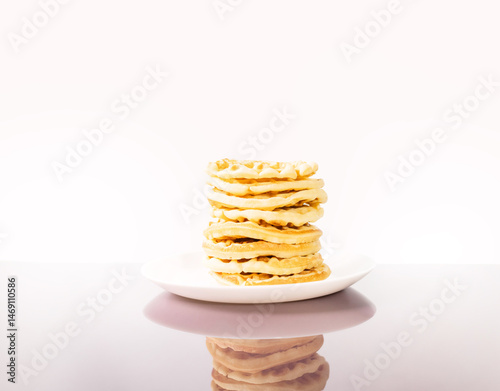many delicious waffles on a plate for breakfast on a light background