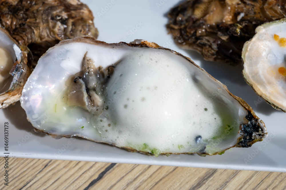Obraz premium Eating of fresh Zeeuwse creuse oysters on farm in Yerseke with living harvested oysters, Oosterschelde, Zeeland, Netherlands.Fresh oysters with lime mousse and mint