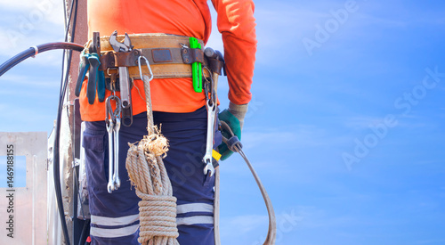 Photos Midsection of electrician with safety belt and work tool is climbing to installi