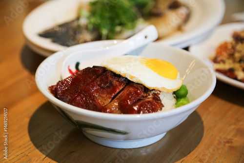 Char siu cantonese BBQ pork rice with fried egg on Hong Kong cuisine restaurant table close up view
