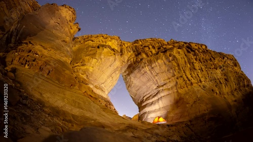 Time lapse of night stars motion while camping tent at bottle shape rock formation near elephant rock in Alula, Madinah, Saudi Arabia