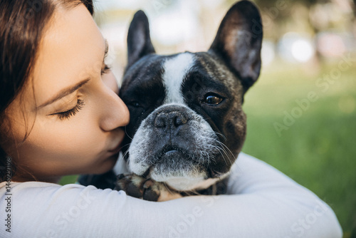 girl holding french bulldog in her arms. girl kissing and having fun with her dog