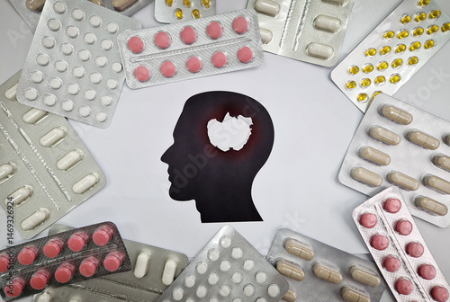 Various blister packs of pills arranged around a head silhouette with an explosion hole inside. Drugs of different shapes and colors for mental problems treatment. Pharmaceutical conceptual background