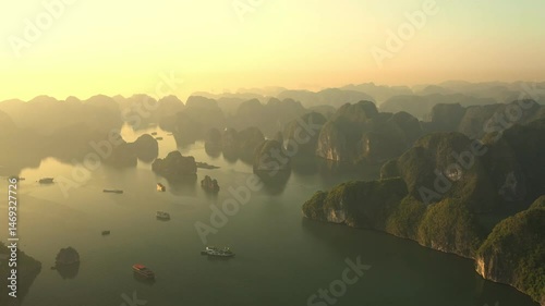 Golden sunrise over Ha Long Bay, Vietnam, with tourist boats navigating the calm waters between lush green islands