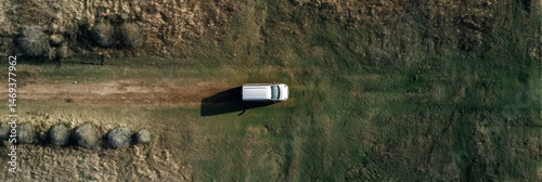 Obraz na płótnie Birds-eye View of a Van Parked on a Dirt Path in an Expansive Open Field Under Bright Sunlight Generative AI w salonie