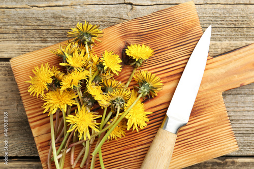 Bild auf Leinwand Dandelion flowers, knife and cutting board on wooden table, top view
