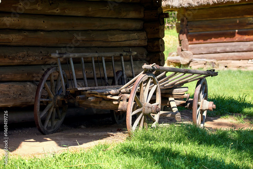  old wooden cart with large wheels standing near a wooden Ukrainian house in the yard