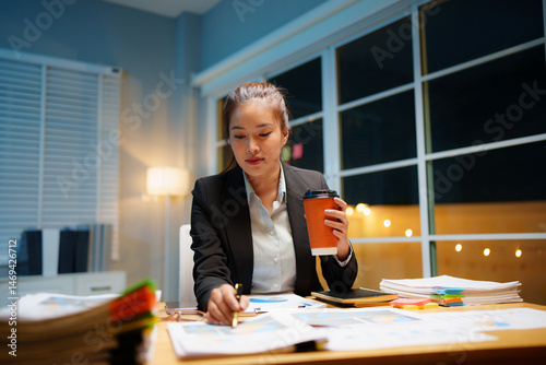 Valokuvatapetti Dedicated businesswoman working late at night in a dimly lit office, focused on her laptop amidst looming deadlines and digital connections — a portrait of modern professionalism and perseverance