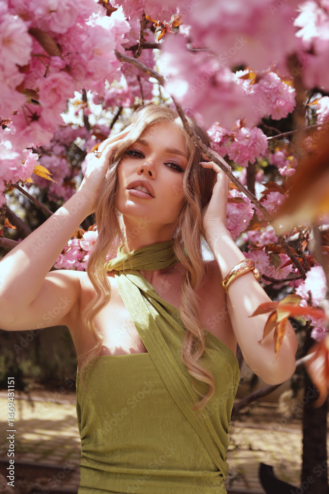 Fototapeta premium beautiful woman with blond hair in elegant dress and accessories posing in blooming sakura garden