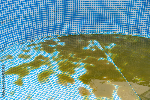 Cleaning of the frame pool, blooming green water. Outdoor pool maintenance in the summer. Sediment at the bottom of the pool.