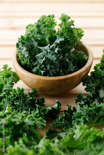 Fresh green Kale leaf salad vegetable in wooden bowl on white background.