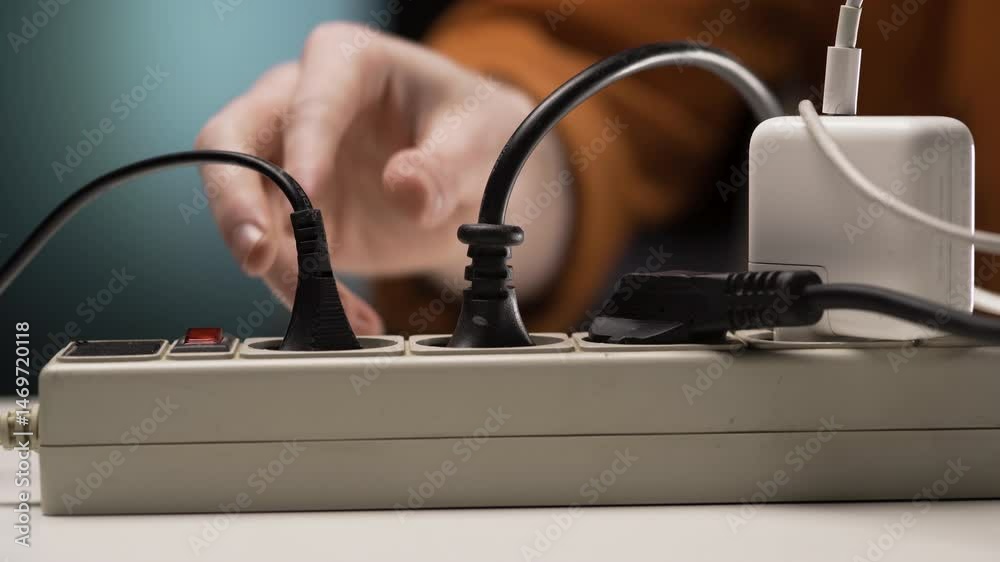 Male hand unplugging power plug. Electrical plug in outlet socket