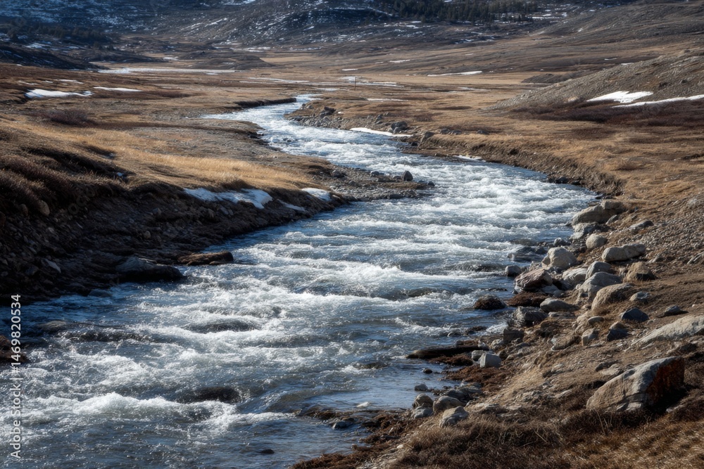 Mountain River Rapids Flowing Through Valley Landscape with Early Season Snow Patches on Grassy Hillsides Mountain River Rapids Flowing Through Valley Landscape with Early Season Snow Patches on Grassy Hillsides