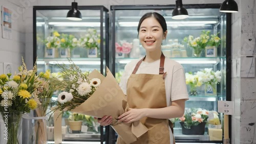 Wallpaper Mural An asian florist in a tan apron holds a fresh bouquet and beams amid rows of chilled blooms. concept of small business success and floral artistry. Torontodigital.ca