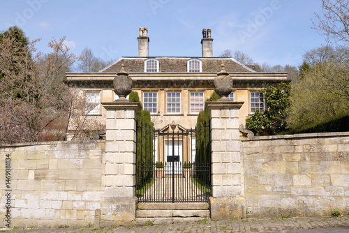 Gated entrance and exterior wall of a beautiful old mansion house on a street in an English town