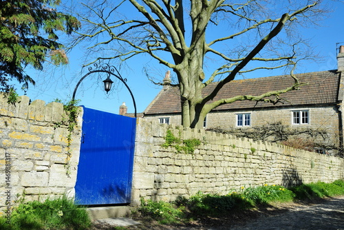Photography Wooden gated entrance with a lantern and stone wall of a beautiful cottage house