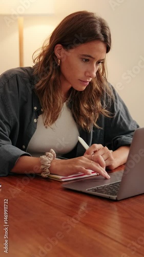 Vertical video, Young woman distance learning online and working on laptop in living room