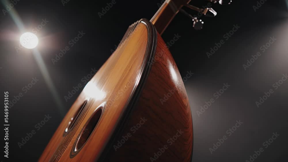 Closeup of polished oud body with dual soundholes under dramatic lighting

