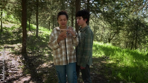 Mother and Son Hiking in Forest, Using Mobile Phone for Navigation