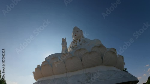 A large white Buddha statue at Wat Huay Pla Kang in Chiang Rai, Thailand, captured from below, with a clear, bright blue sky in the background.