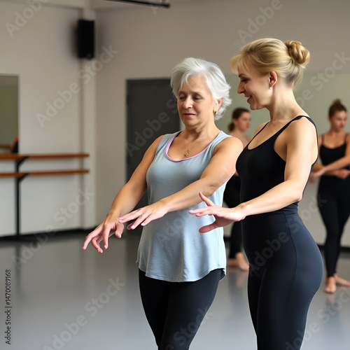 Experienced elderly female ballet teacher guiding younger woman through beginner ballet positions in choreography studio during group class