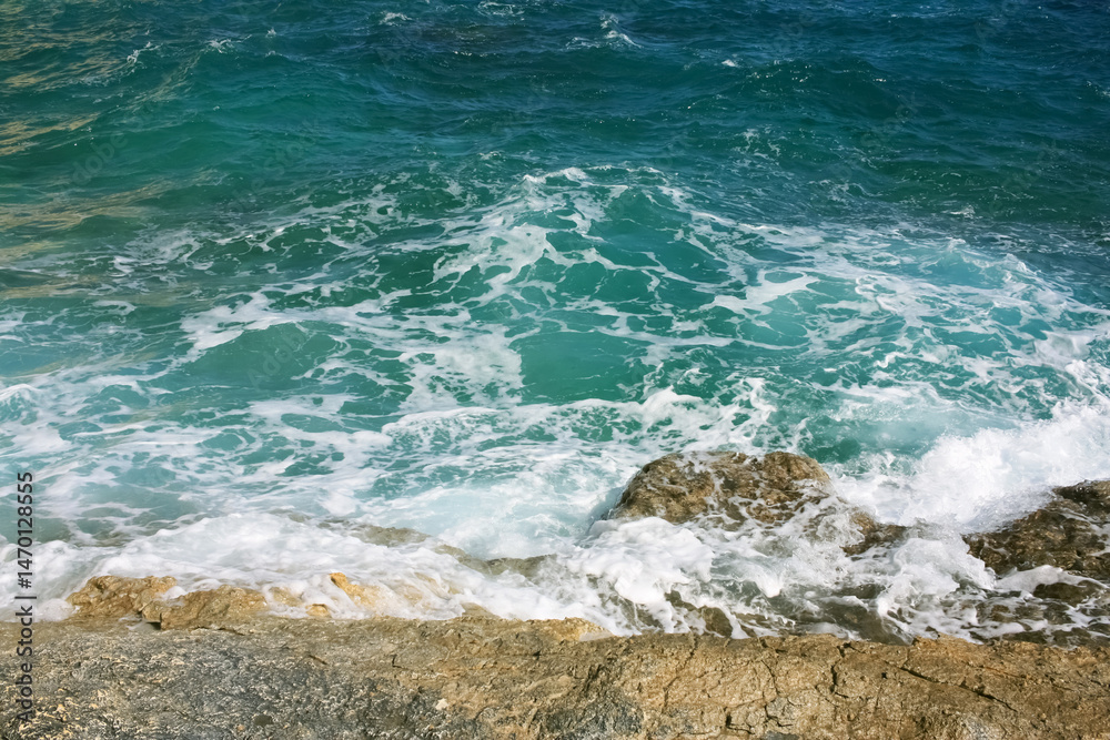 Fototapeta premium Ocean waves hitting rocks, sea foam, beach