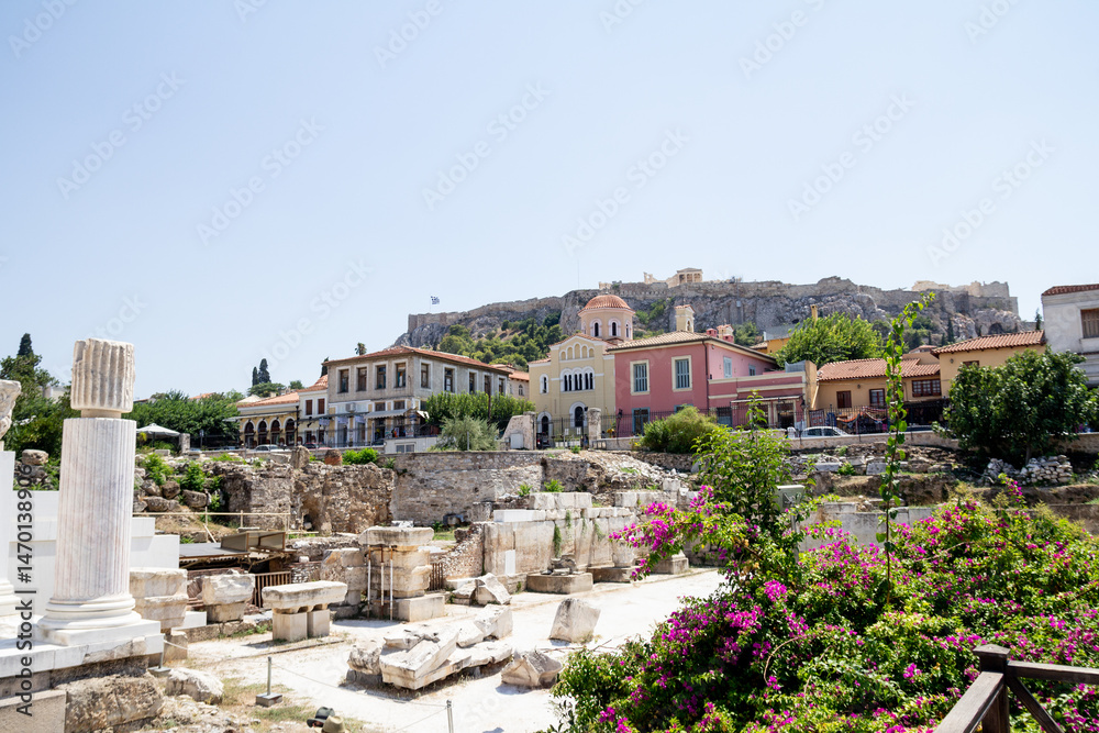 Naklejka premium A bright and colorful photo taken in Athens, Greece, showing blooming flowers in the foreground with ancient ruins in the background. The image captures a relaxed, sunny holiday atmosphere blending hi