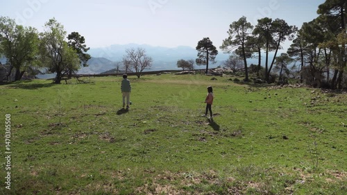Children Playing Soccer in a Mountain Meadow: Family Fun on a Sunny Day