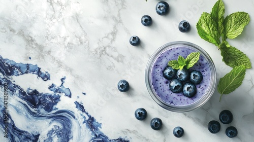 Blueberry smoothie in a glass, garnished with fresh mint leaves and blueberries, arranged on a marble surface photo