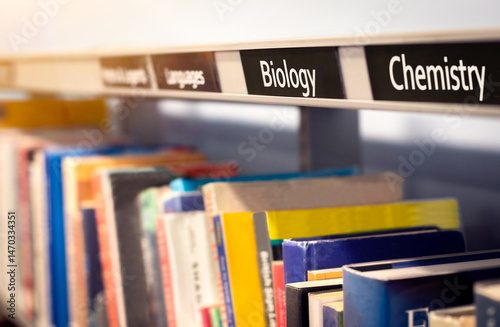 Books stacked on shelf under science categories of Biology and Chemistry. Non-fiction library or bookstore scene depicting factual reference books. Concept of school, knowledge, education and study.