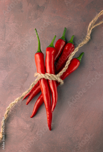 five red hot peppers tied with a rope on a red background