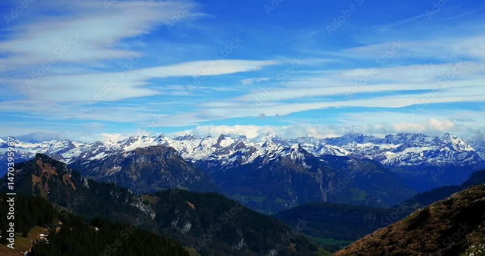 Majestic mountain range with snow-capped peaks under a bright blue sky during a sunny afternoon Majestic mountain range with snow-capped peaks under a bright blue sky during a sunny afternoon
