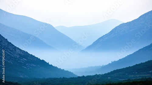 Misty mountain valley panorama in soft blue hues.