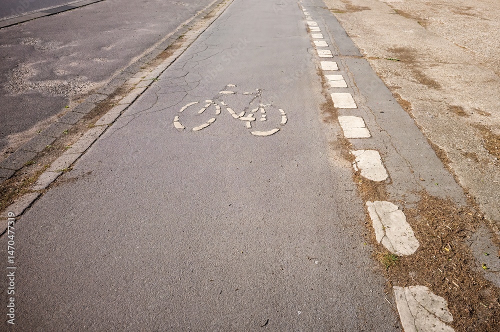 Fototapeta premium Bike lane symbol showing through cracked asphalt on city street