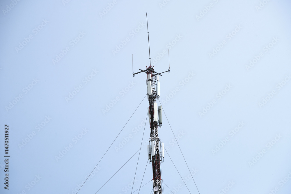 Communication tower against clear blue sky with antennas and support cables Communication tower against clear blue sky with antennas and support cables