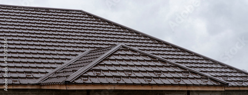 Foto Brown wet roof made of metal tiles with diagonal joints