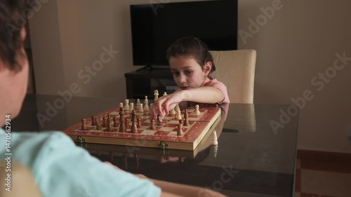 Siblings Engage in a Chess Match at Home: A Display of Strategy and Playful Competition
