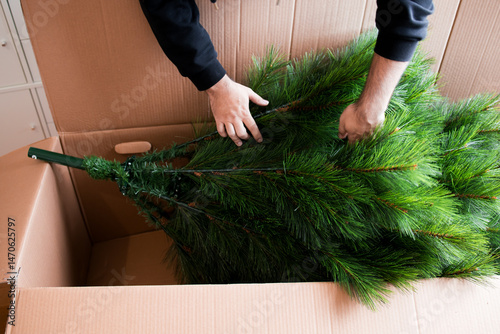 Adult caucasian male assembling artificial Christmas tree from cardboard box