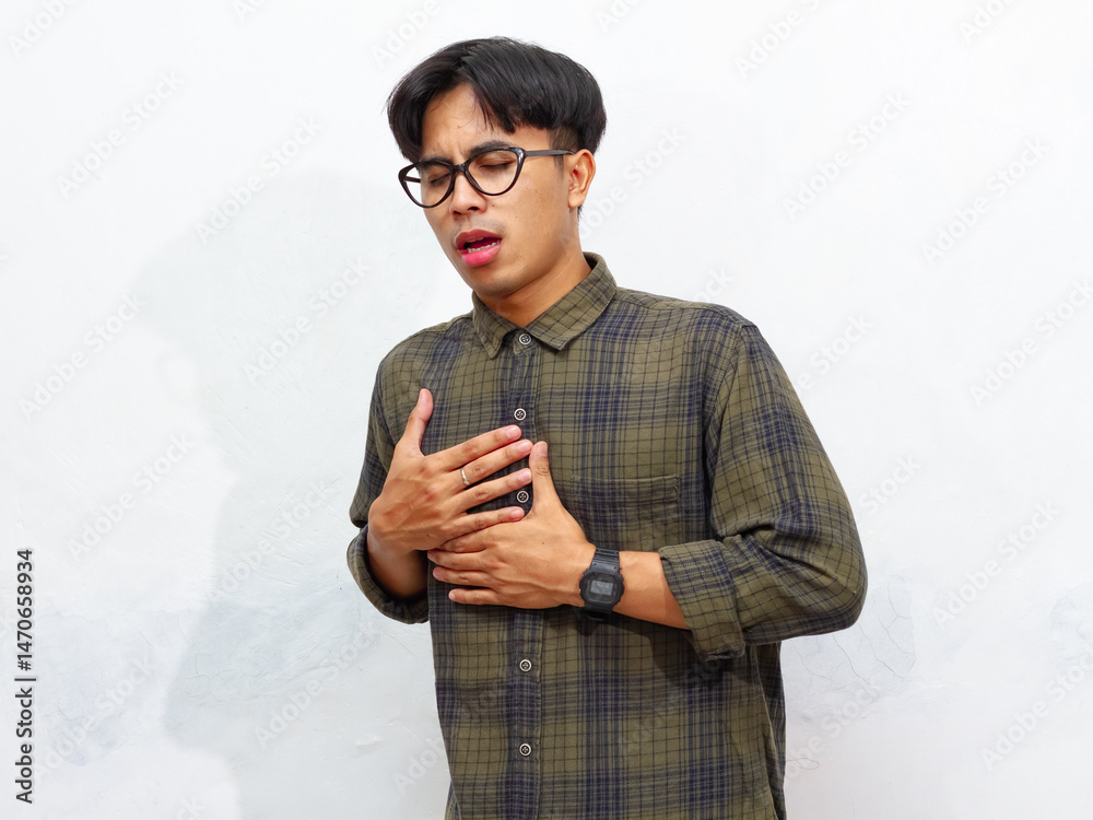 Fototapeta premium unhealthy Young Asian man with a pained and sad expression holding his right chest isolated on a white background.