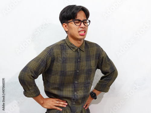 Young Asian man holding his stomach with a pained and sad expression, isolated on a white background.