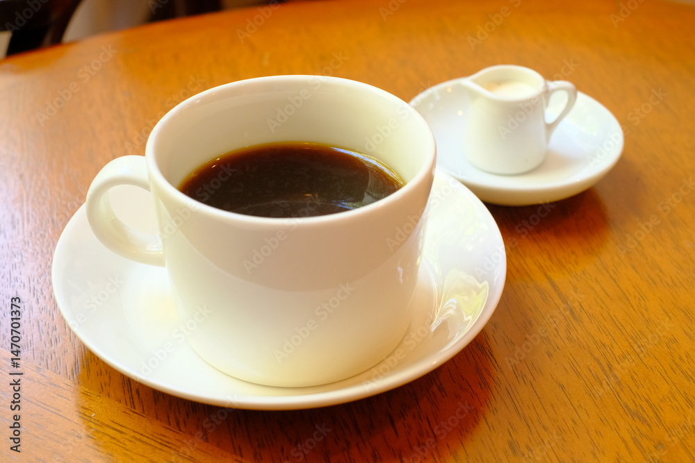 cup of coffee with milk pitcher on wooden table cup of coffee with milk pitcher on wooden table