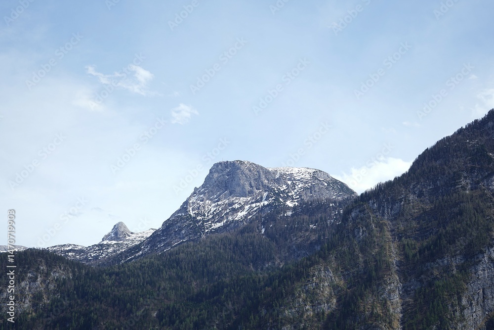 Fototapeta premium Scenic view of Hallstatt, Austria — charming alpine town with traditional architecture, swans on the lake, boats, and majestic mountains in the background. A picturesque travel destination.
