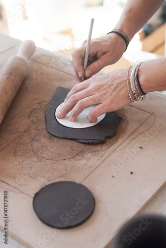 Ceramist cutting a thin sheet of clay with a punch in a luminous studio