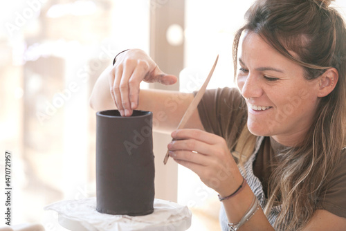 Female ceramic artist trimming pottery with tools