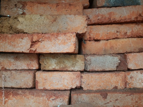 A stack of old, weathered red bricks with rough textures and varying shades of orange and brown.
