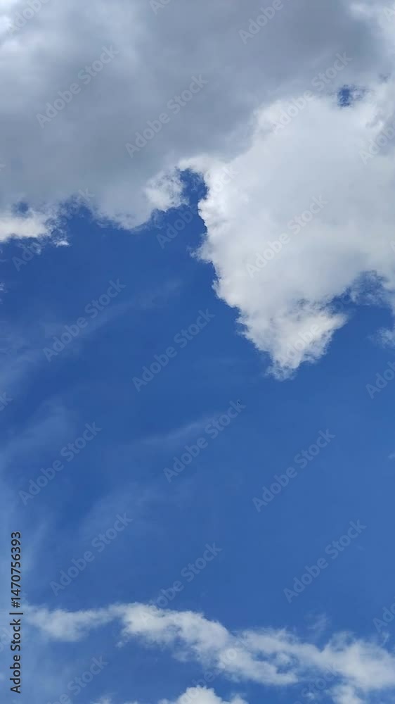 Un cielo de azul con varias nubes de color blanco y gris con un movimiento lento. Video vertical