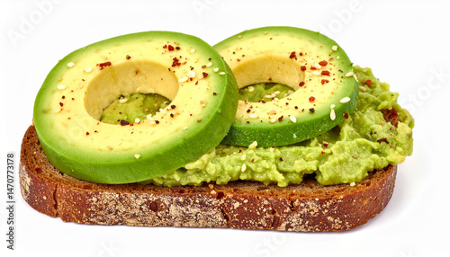 on a plain white surface, a piece of dark colored bread has a generous helping of light green, pulpy matter spread across it